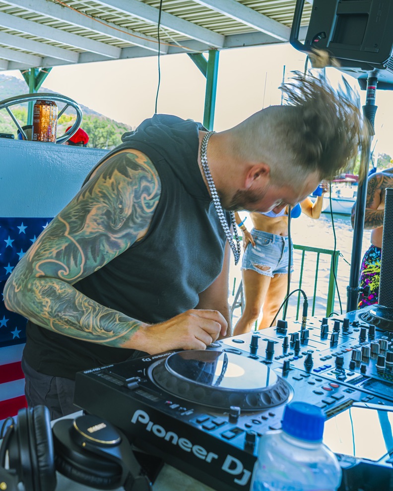 artefex leaning over the DJ decks during the July 4, 2026 performance on Town Lake in Austin